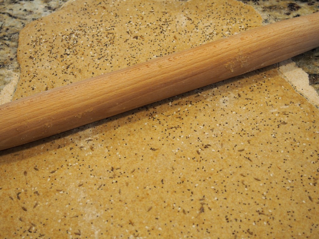 Using your rolling pin, lightly roll the seeds onto the crackers.